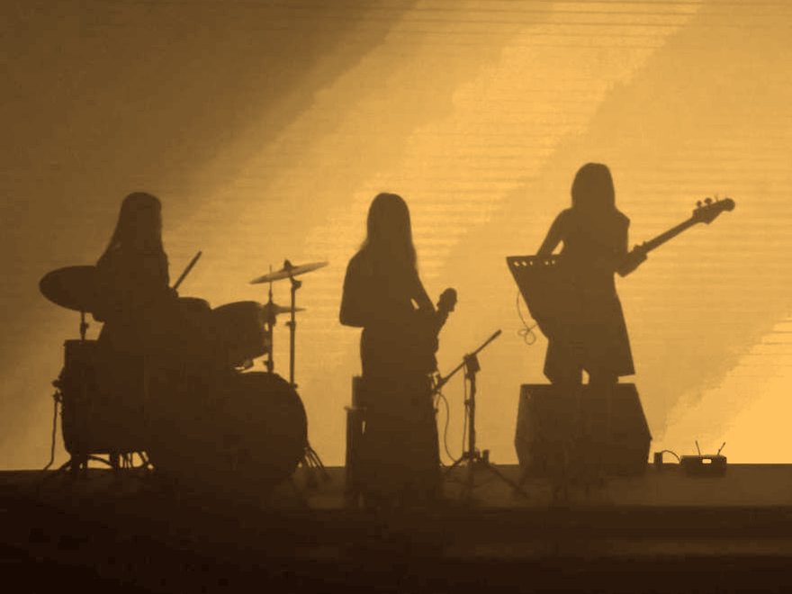 Banda tocando em silhueta — bateria, violão e baixo