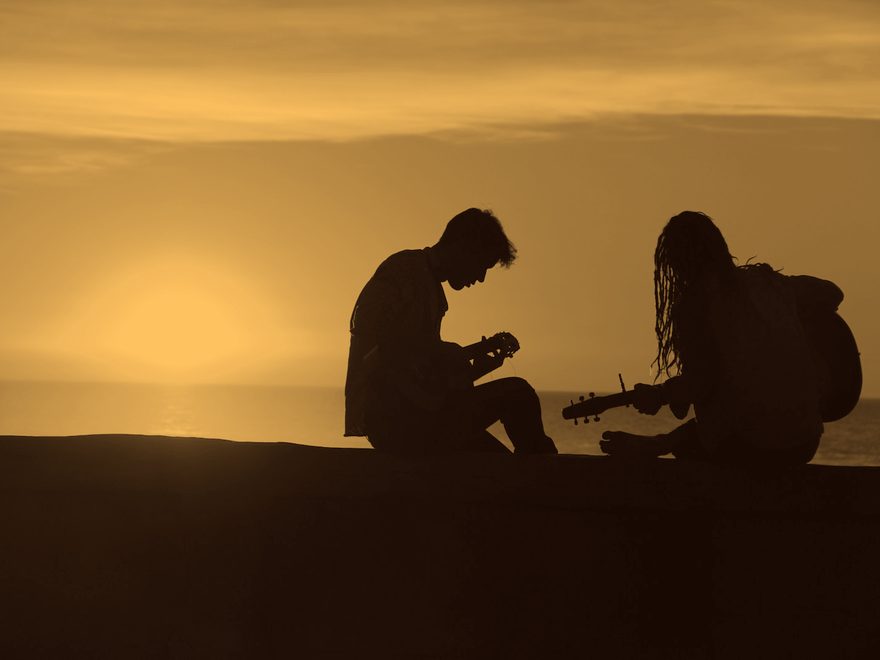 Dois violonistas tocando em silhueta no pôr do sol